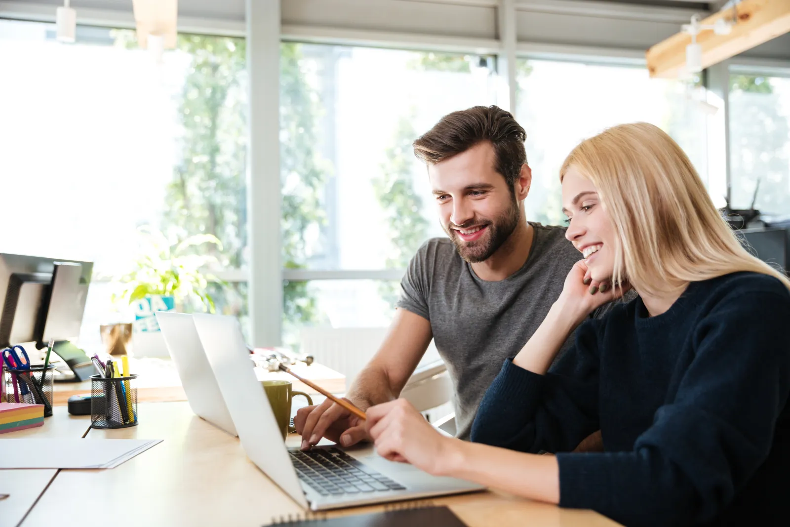 Two colleagues at a laptop in a bright office